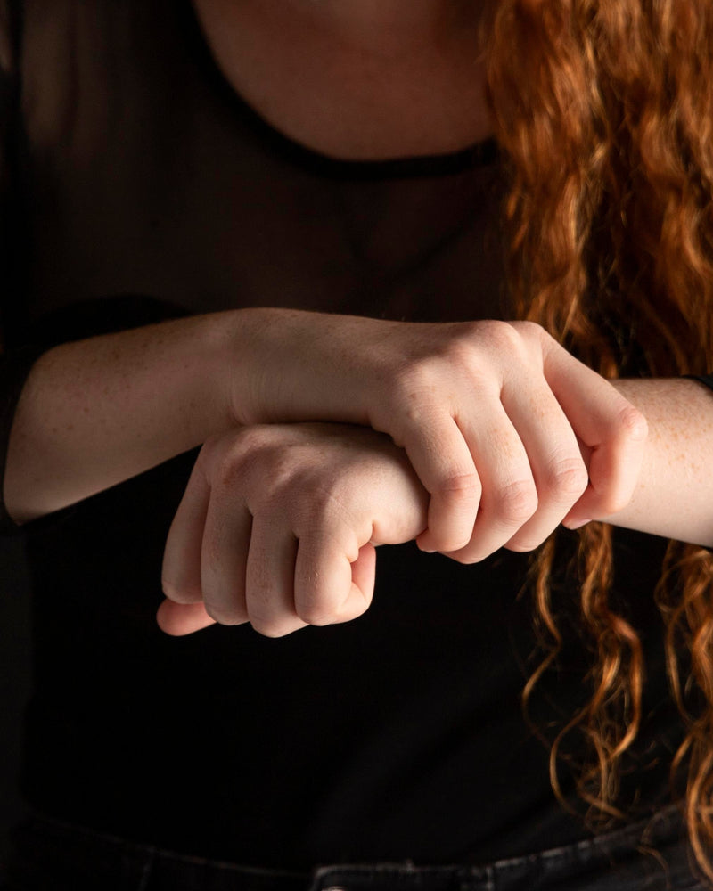 Gros plan sur les mains d’une femme en train de signer en langue des signes sur fond sombre