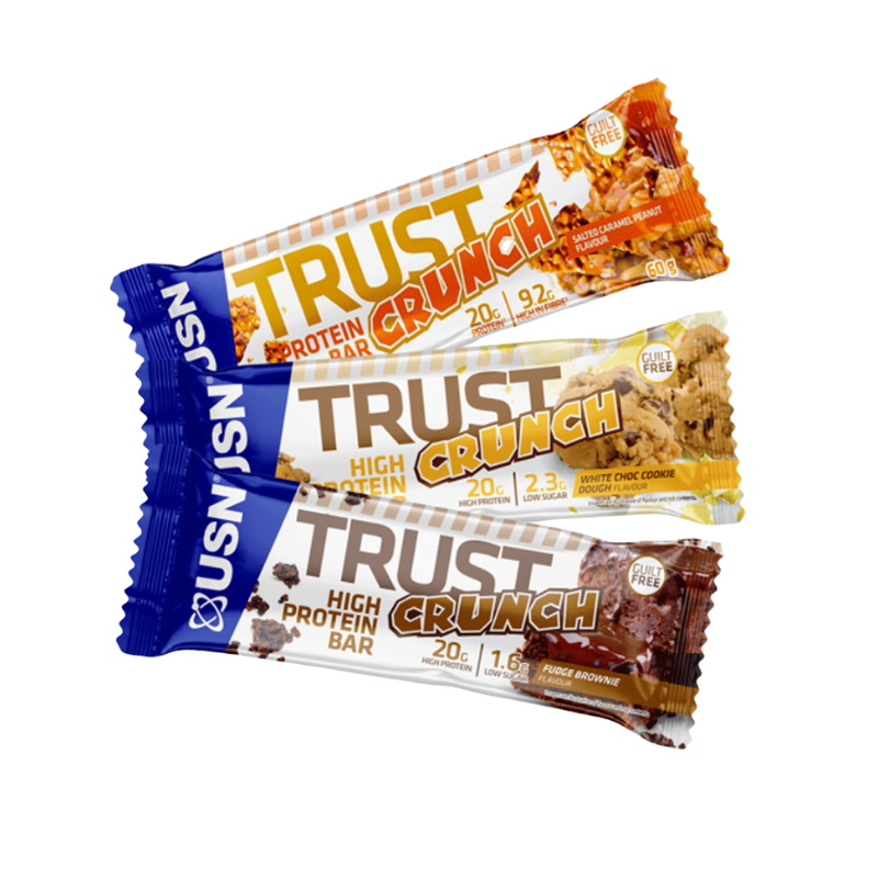 Trois barres USN Trust Crunch alignées présentant les saveurs salted caramel peanut, white choc cookie dough et fudge brownie, chacune avec 20 g de protéines