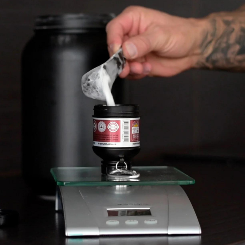 Réservoir entonnoir Smartshake Whey2Go posé sur une balance pendant le remplissage de poudre protéinée