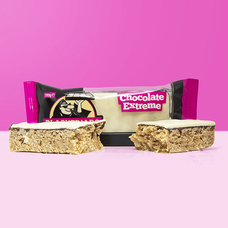 Barre flapjack Blackfriars Chocolate Extreme avec couche de chocolat blanc, présentée en deux morceaux devant l’emballage noir et fuchsia sur fond rose vif