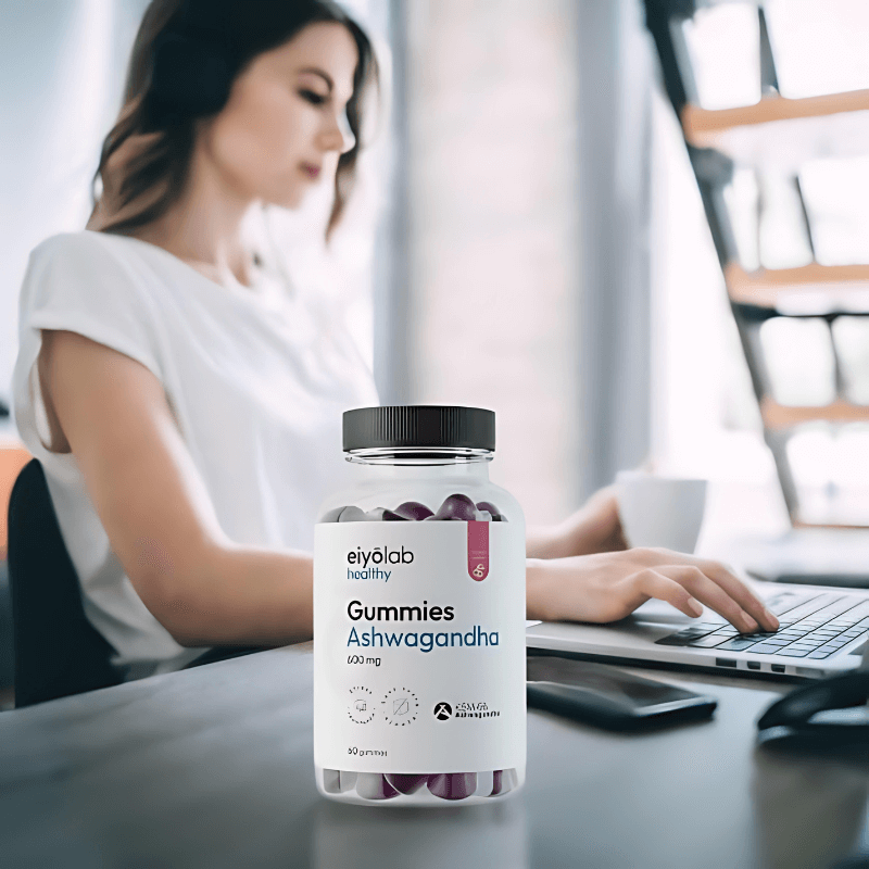 Pot Eiyolab Gummies Ashwagandha posé sur un bureau devant une femme travaillant sur ordinateur, illustrant la gestion du stress au quotidien