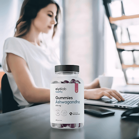 Pot Eiyolab Gummies Ashwagandha posé sur un bureau devant une femme travaillant sur ordinateur, illustrant la gestion du stress au quotidien