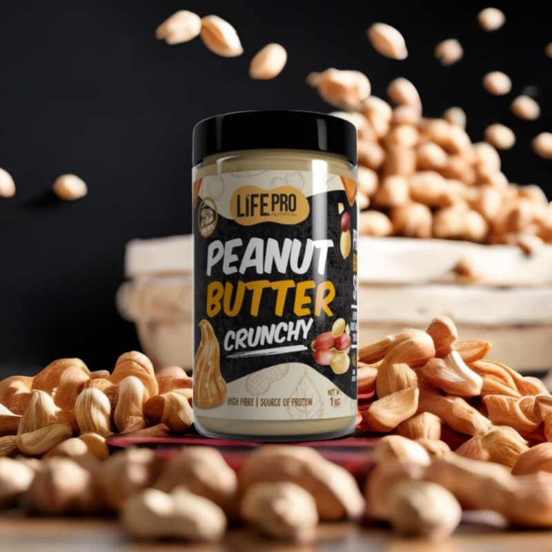 Pot de beurre de cacahuète LifePro Peanut Butter Crunchy 1 kg posé au milieu de cacahuètes entières sur fond sombre pour illustrer une texture croquante riche en fibres