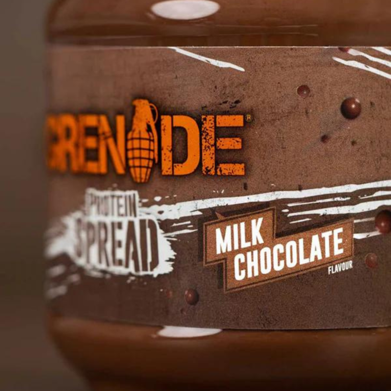 Gros plan sur l’étiquette de la pâte à tartiner protéinée Grenade saveur chocolat au lait avec logo orange et fond marron texturé