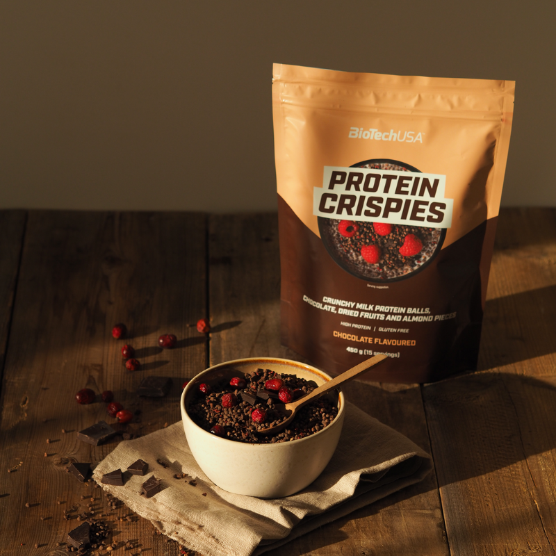 Sachet de Protein Crispies BiotechUSA chocolat 450 g montrant un bol de billes protéinées au chocolat avec framboises, mention high protein et gluten free sur un emballage beige et marron