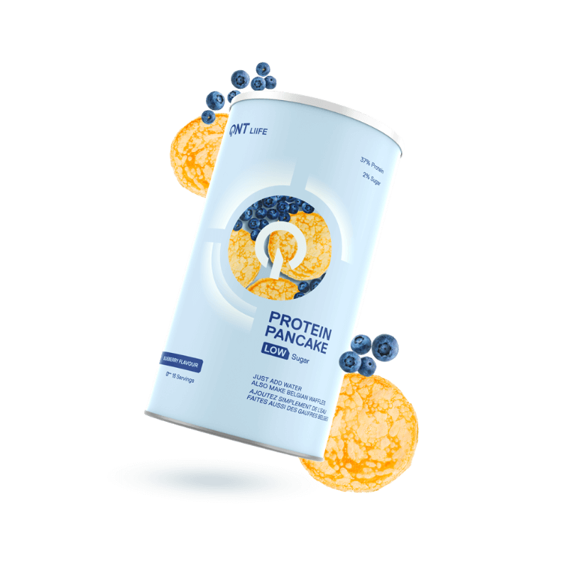 Boîte cylindrique QNT Protein Pancake low sugar goût myrtille entourée de pancakes dorés et de myrtilles fraîches sur fond blanc