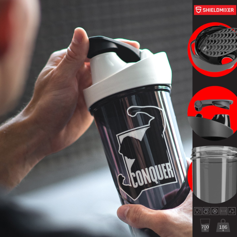Shaker Shieldmixer Conquer noir 700 ml tenu en main avec couvercle blanc et noir en situation d’entraînement