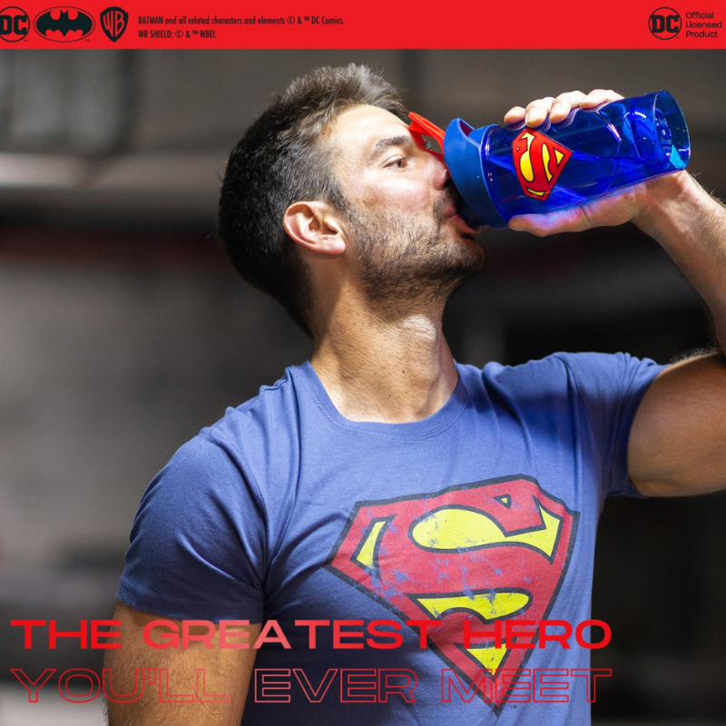 Athlète buvant dans un shaker bleu Superman 700 ml avec logo rouge et jaune pendant son entraînement